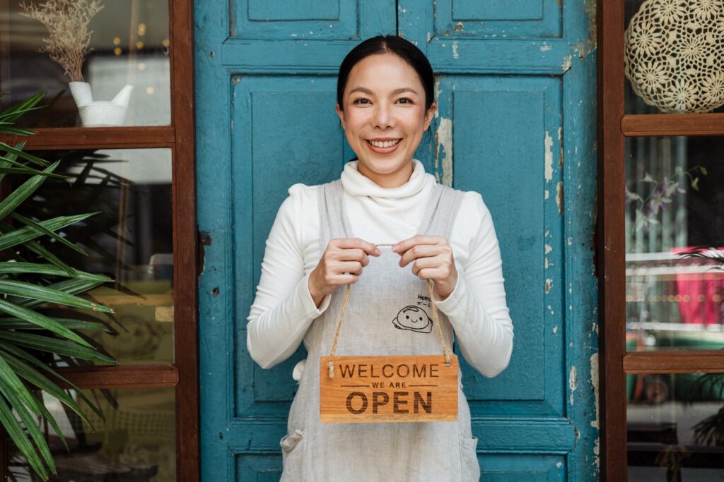 A woman looking happy to open the door of her business.