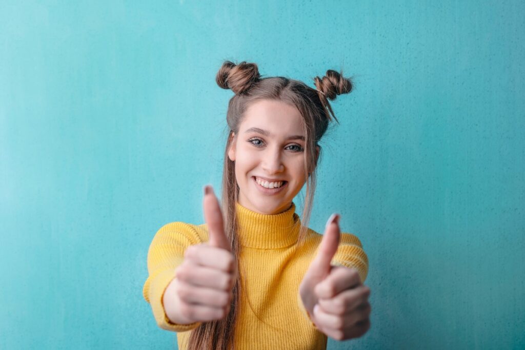 Woman in Yellow Turtleneck Sweater Smiling with a Thumbs Up to inspire readers to write to us about our motivational blog.