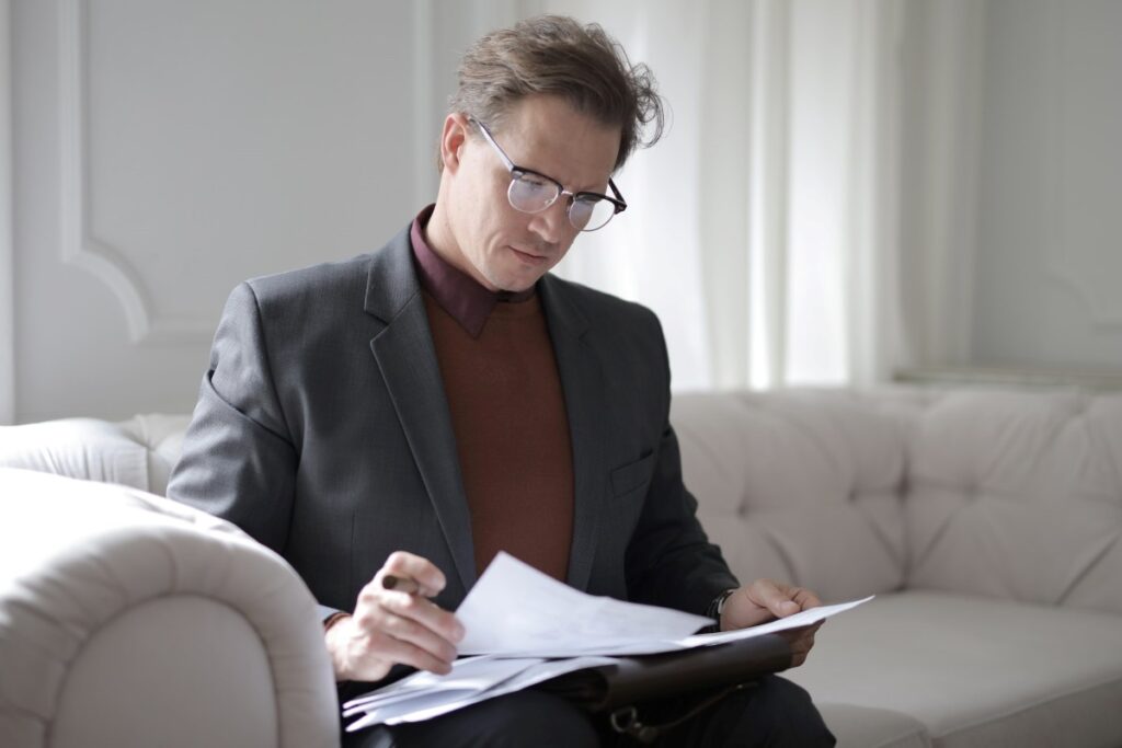 Executive male reading a disclaimer document on a couch.